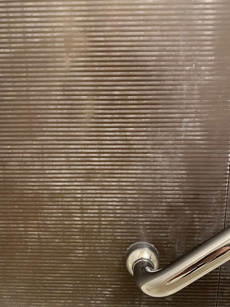 清掃前の壁面には白っぽい石鹸カスが広い範囲に付着している
